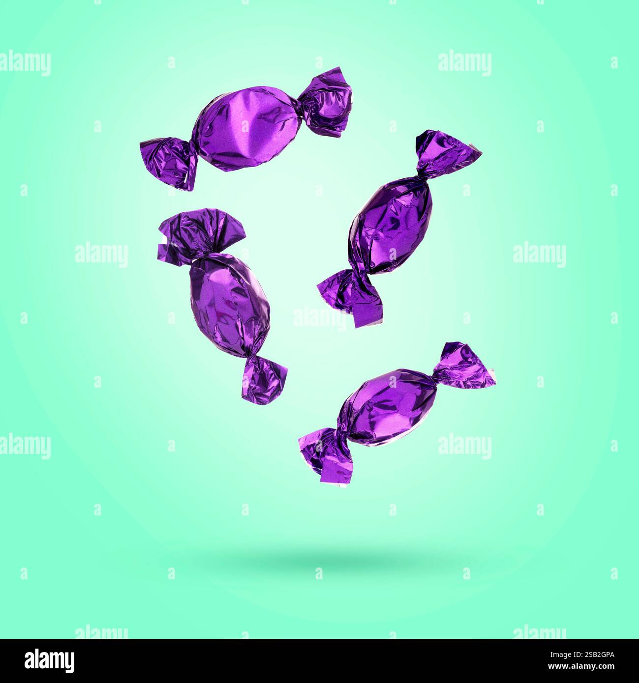 Candies in bright wrappers falling on turquoise background Stock Photo