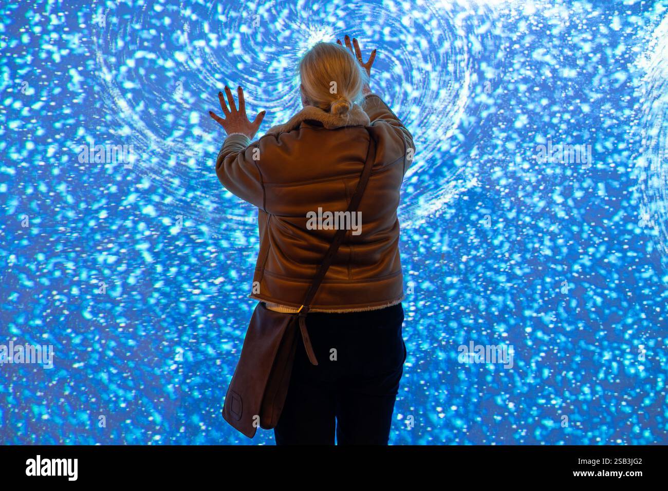 Bristol, UK. 31st Jan, 2025. A woman is pictured as she interacts with the light installation titled 'Tetra' by Ottomata in The Podium, Broadmead. Tetra is an audio-visual experience inspired by the cosmos and the many forces of nature that invites audiences to control the visuals and sounds of the installation by using their entire bodies to interact with it. Ottomata formed in Montreal in 2017, is a studio that specialises in interactive media for the public space in order to create truly immersive experiences. Credit: Lynchpics/Alamy Live News Stock Photo