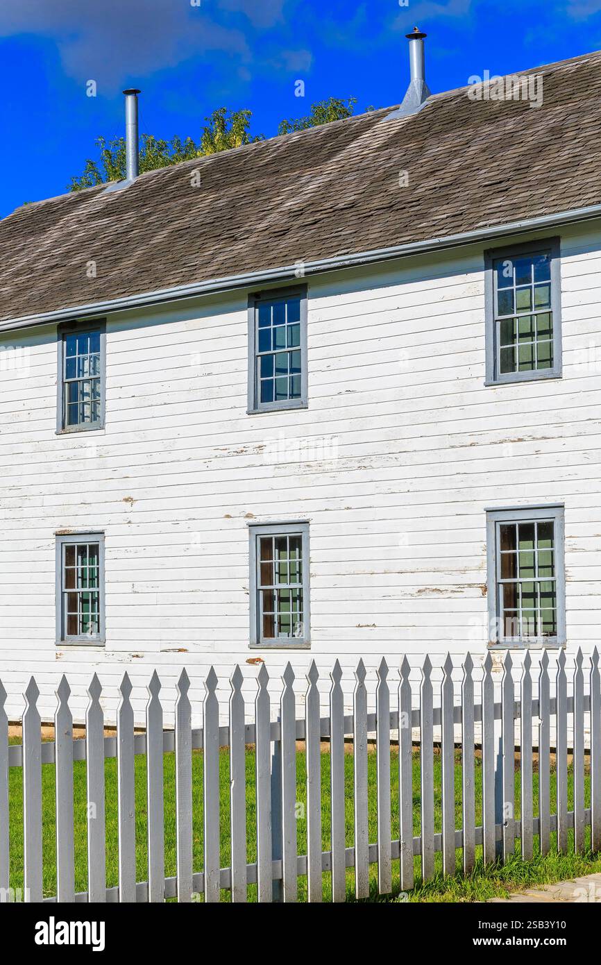 A white house with a white fence and a white roof. The house has a lot ...