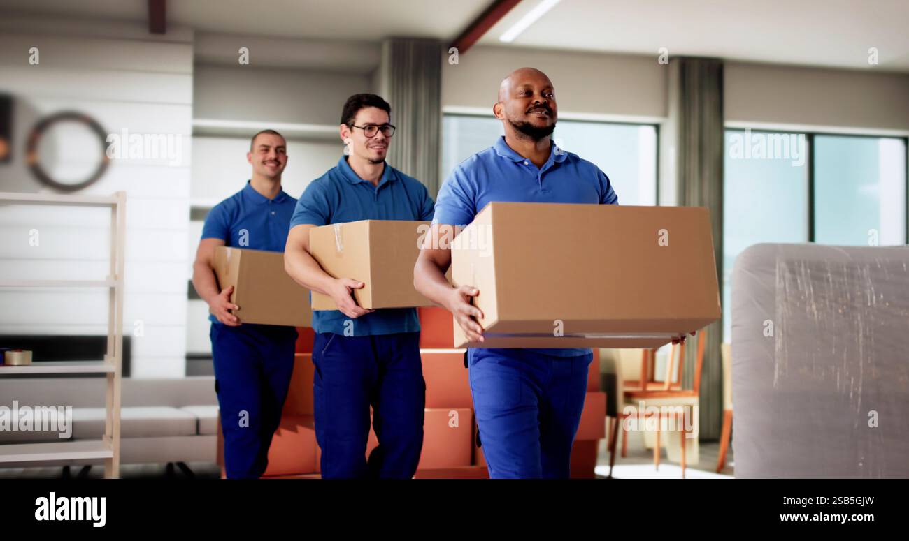 Professional Movers Smiling While Holding Boxes in Residential Room Stock Photo