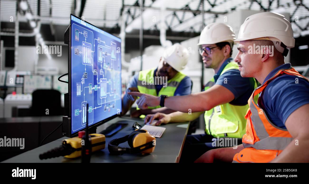 Diverse group of operators using SCADA system at modern factory. Stock Photo