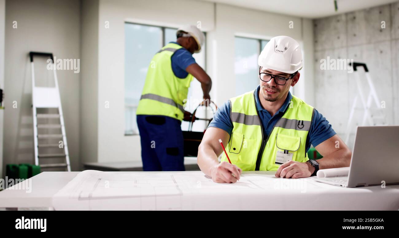 Professional foreman worker uses laptop to communicate on construction site. Stock Photo