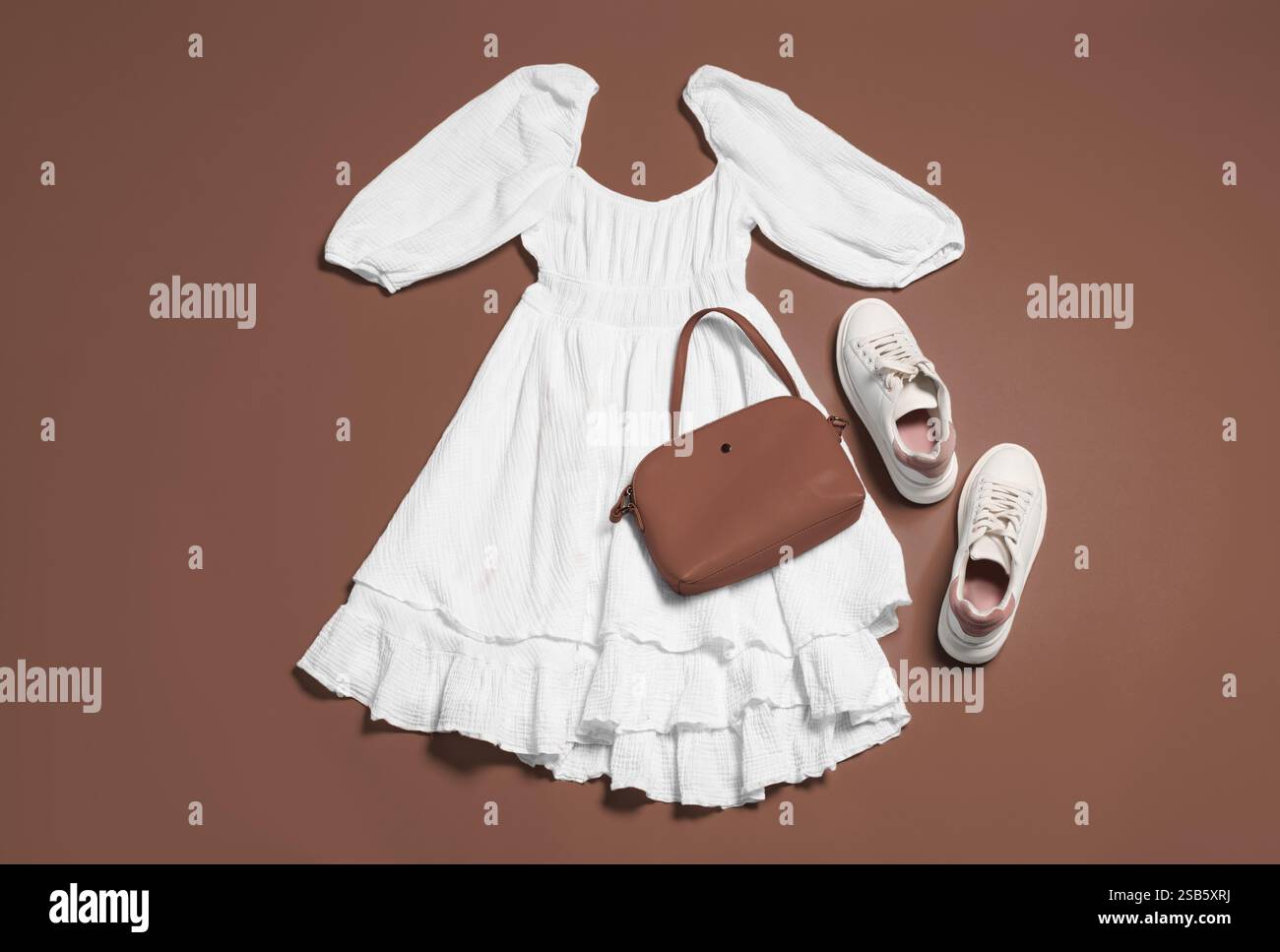Stylish outfit with bag in mocha mousse shade on brown background, flat ...
