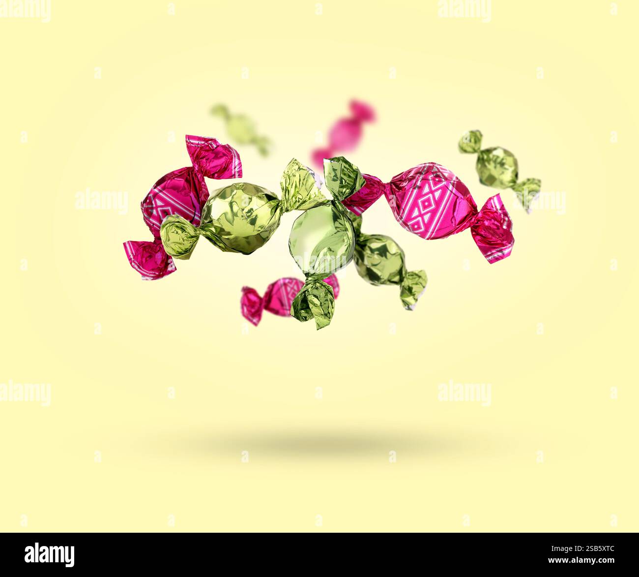 Candies in bright wrappers falling on beige background Stock Photo