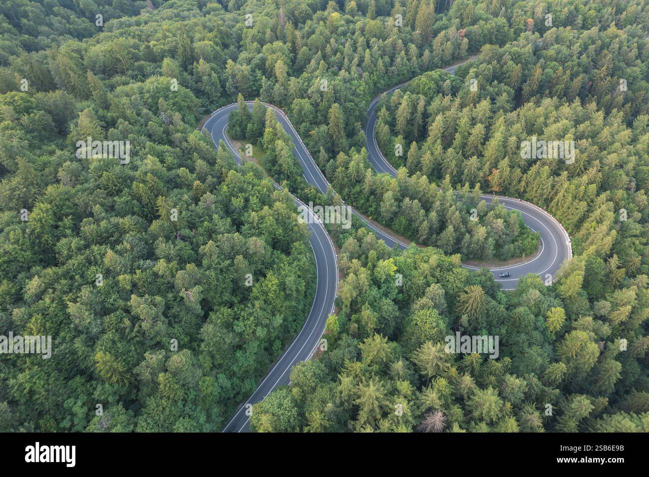 Aerial view of scenic winding mountain road cutting through the green ...