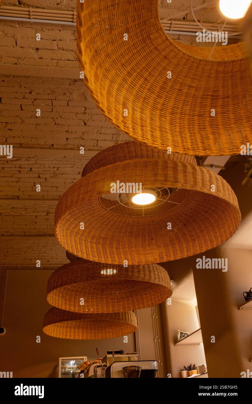 Handmade wicker rattan chandelier hanging at cafeteria in beautiful morning light. Rattan lantern lamps. Stock Photo
