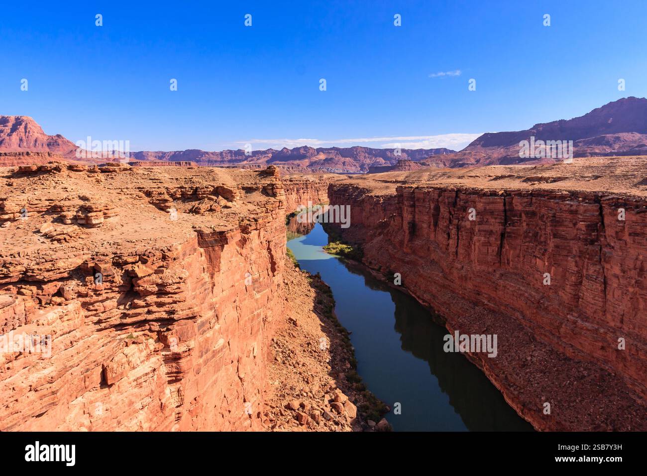 A river runs through a canyon with a clear blue sky above. The canyon ...
