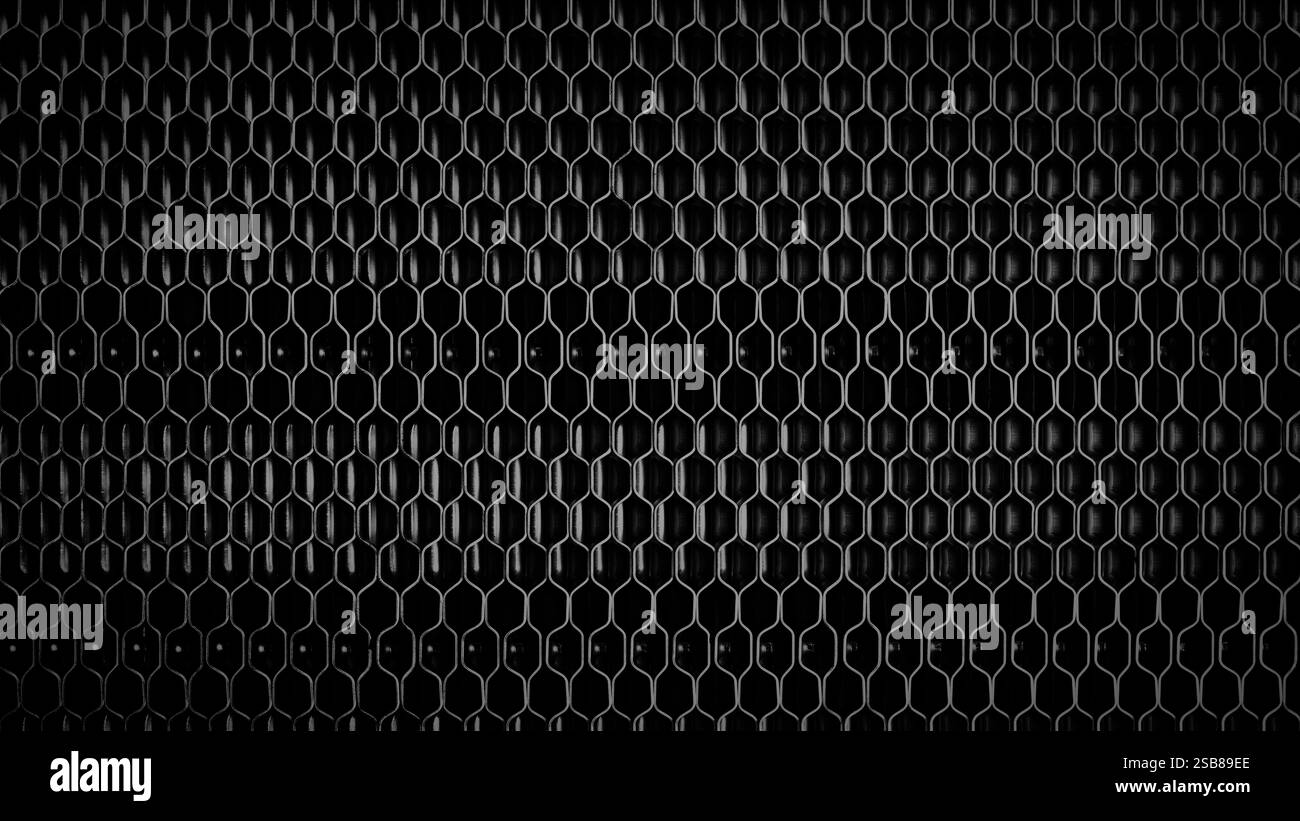A black and white photo of a metal mesh with a black background. The ...