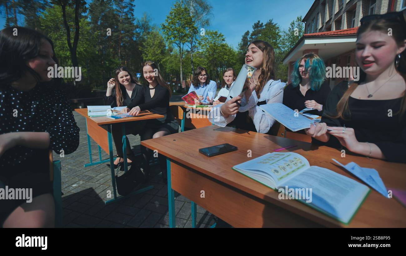 Cheerful students are actively participating in an outdoor lesson, enjoying the pleasant weather and engaging in their studies Stock Photo