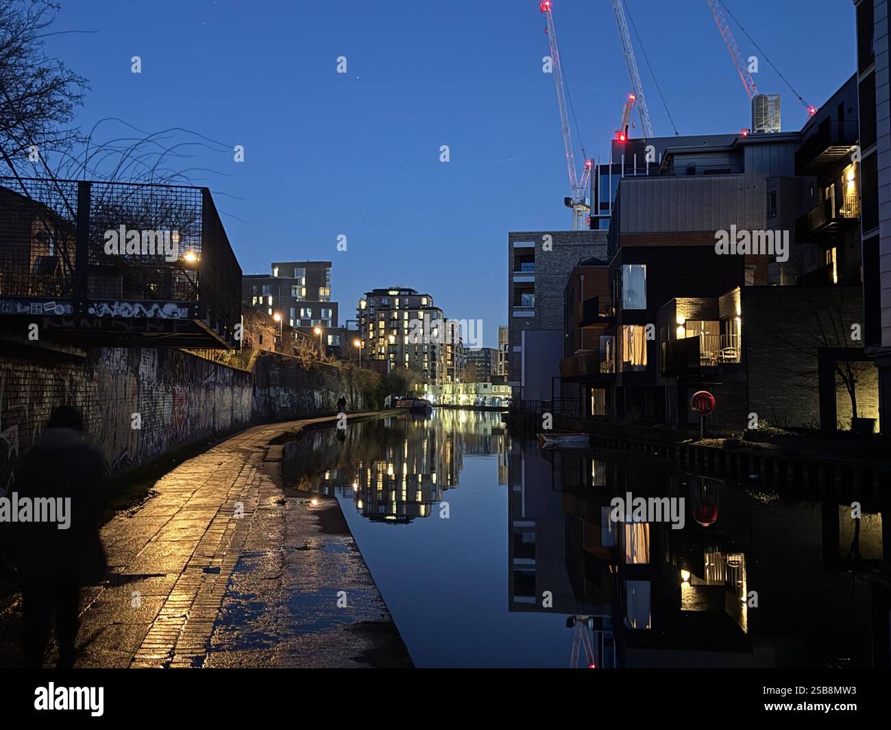 Nighttime reflection on the water of Regent's Canal in London, England, walking path, tow path, brick sidewalk - Smartphone Captured Stock Image