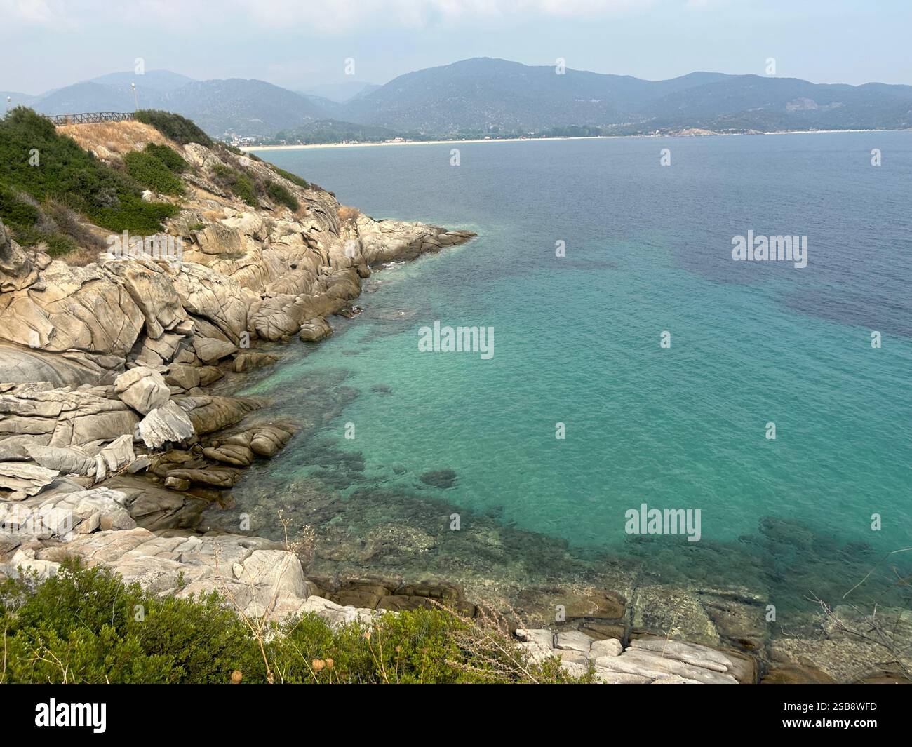 Turquoise Water and Rocky Coastline Under Clear Sky - Smartphone Captured Stock Image