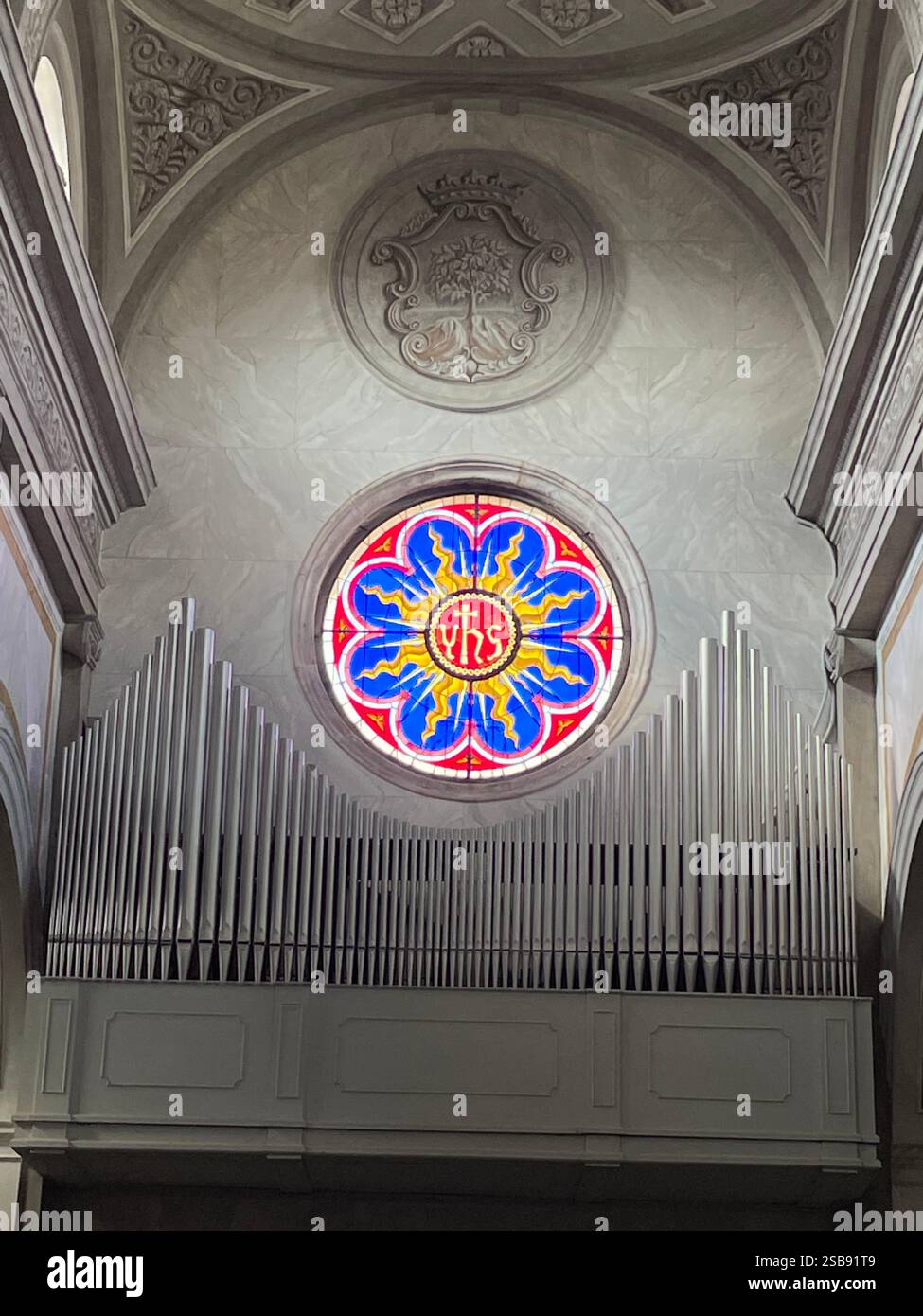 Noci, Italy. Interior of the medieval Church of Saint Mary and Saint Roch (Chiesa madre). Rose window with the IHS monogram. - Smartphone Captured Stock Image