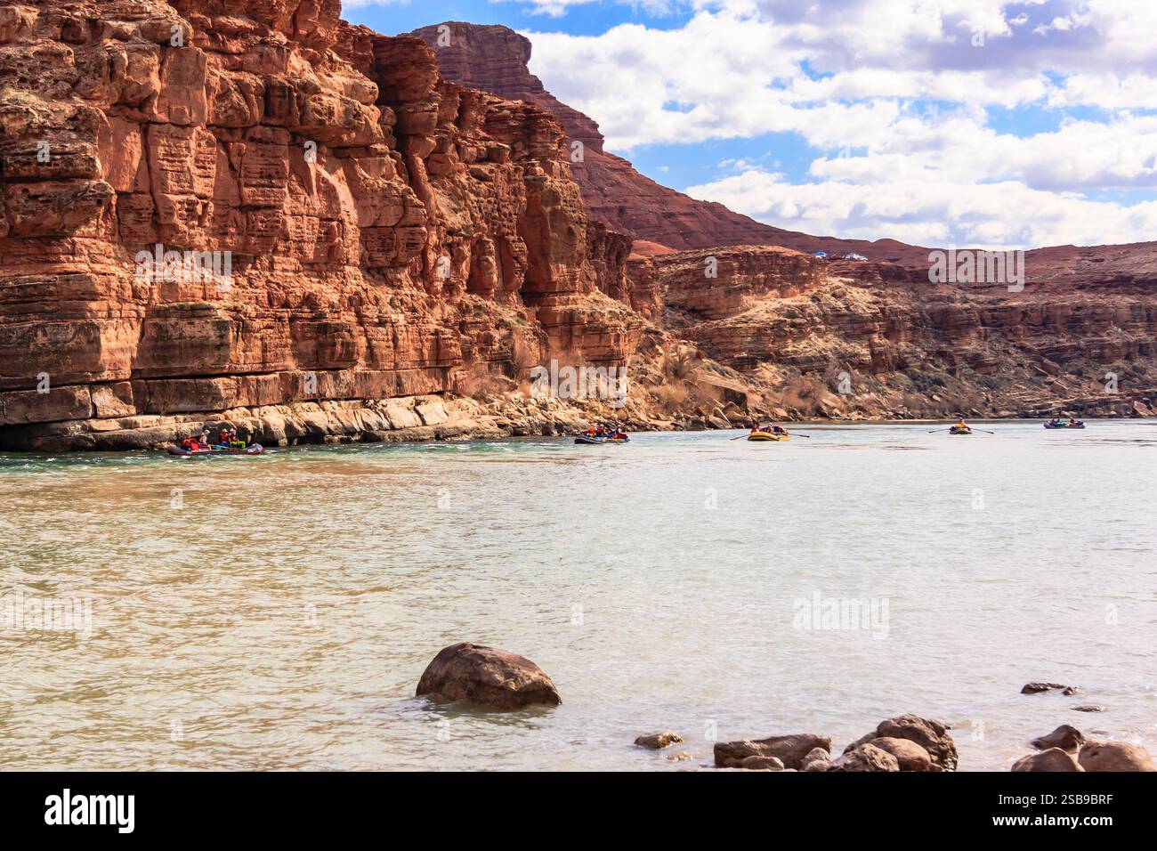 A group of people are rafting down a river in a canyon. The water is ...