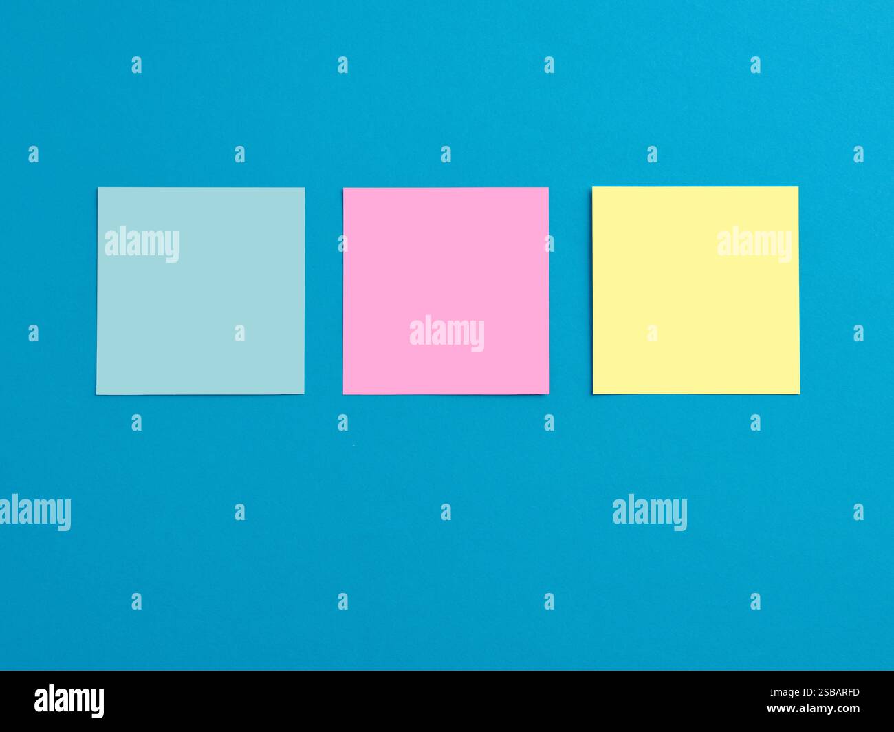 Empty blank colorful note papers attached on blue board background. Stock Photo