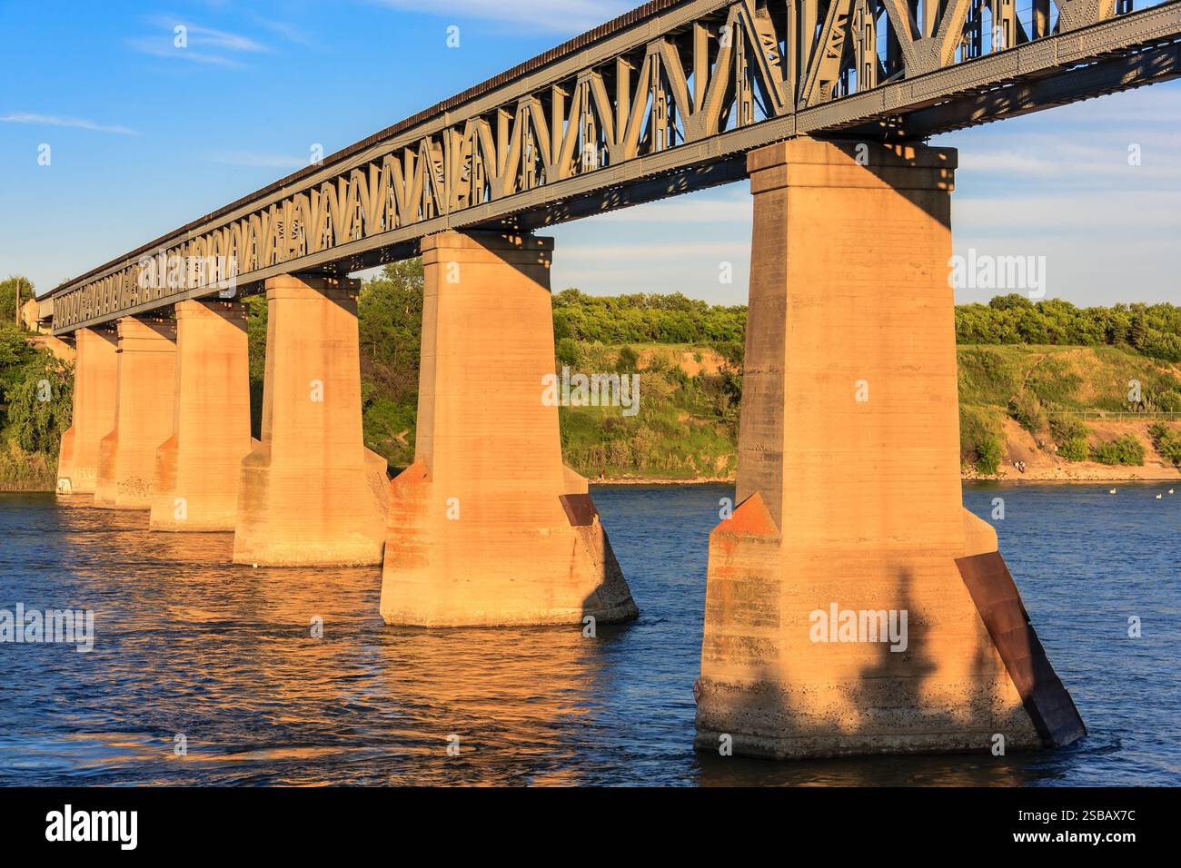 A bridge spans a river with a view of the water below. The bridge is made of stone and has four pillars Stock Photo