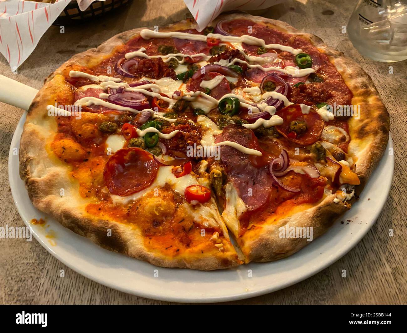Close up view of a pizza at a gastro-pub with cheese, tomato, pepperoni, fed onion and chillies. - Smartphone Captured Stock Image