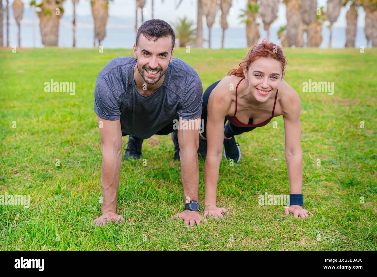Fit couple exercising outdoors doing push-ups on the grass in a park Stock Photo