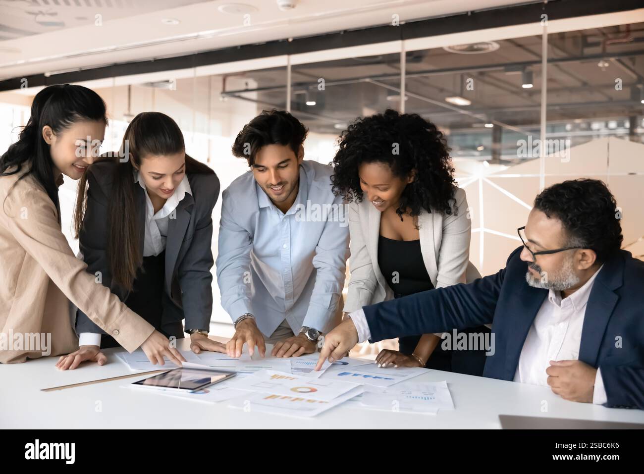 Positive diverse different aged colleagues analyzing statistic paper reports together Stock Photo