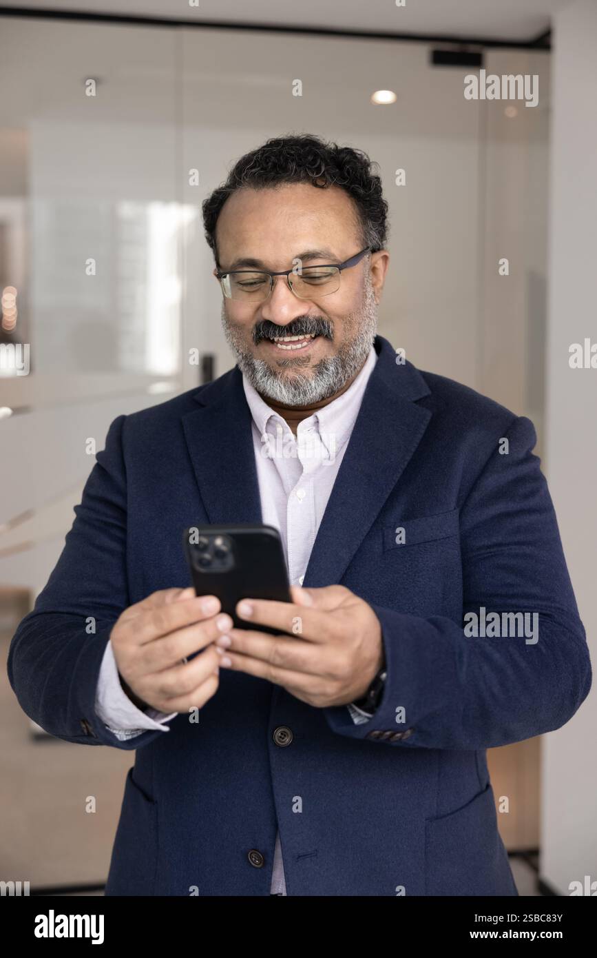 Happy senior Indian executive man using mobile phone Stock Photo