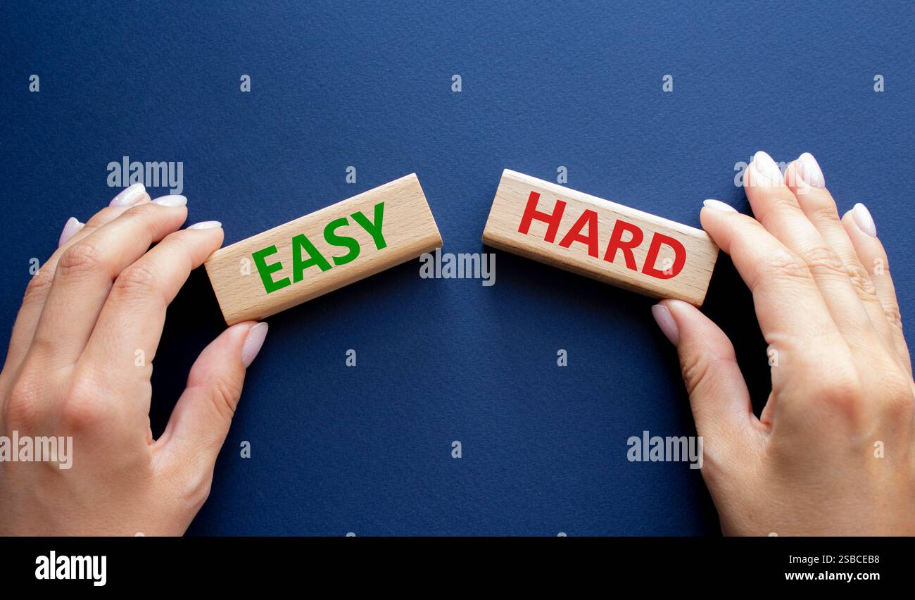 Easy or Hard symbol. Concept word Easy or Hard on wooden blocks. Businessman hand. Beautiful deep blue background. Business and Easy or Hard concept. Stock Photo