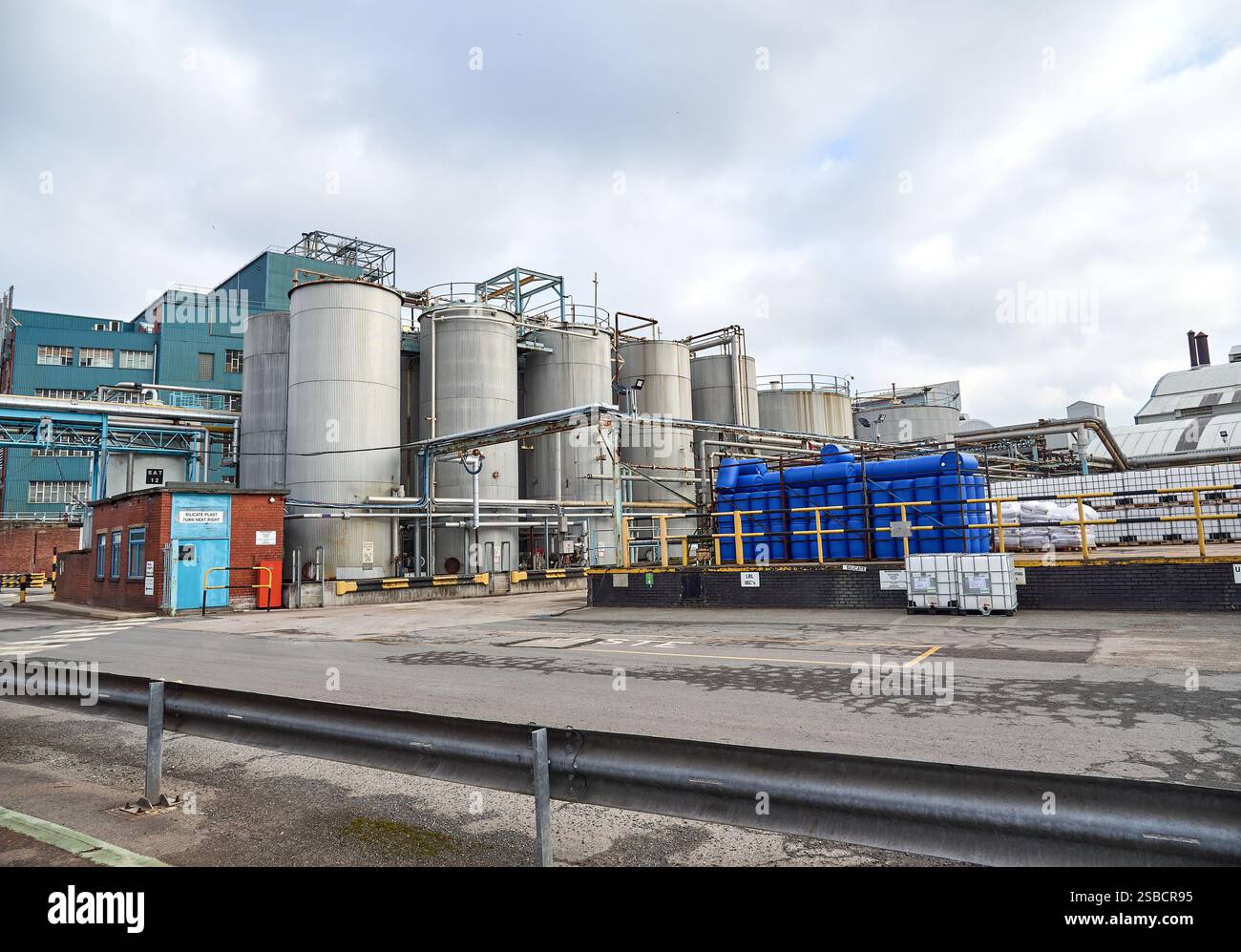 Industrial facility with large metal chemical tanks and blue piping ...