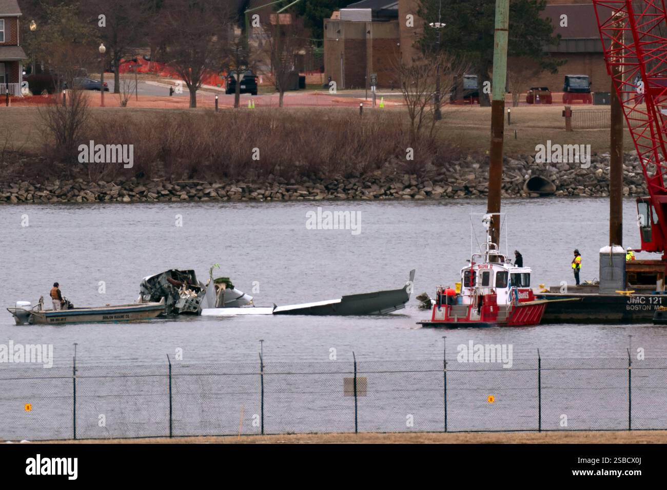 Rescue and salvage crews with a crane work near the wreckage of an ...