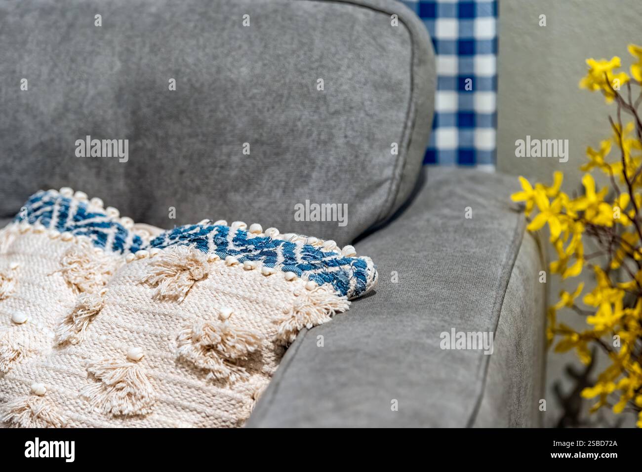 Pillow on grey couch sofa in modern apartment, house or home with staging of large gray furniture and yellow flowers Stock Photo