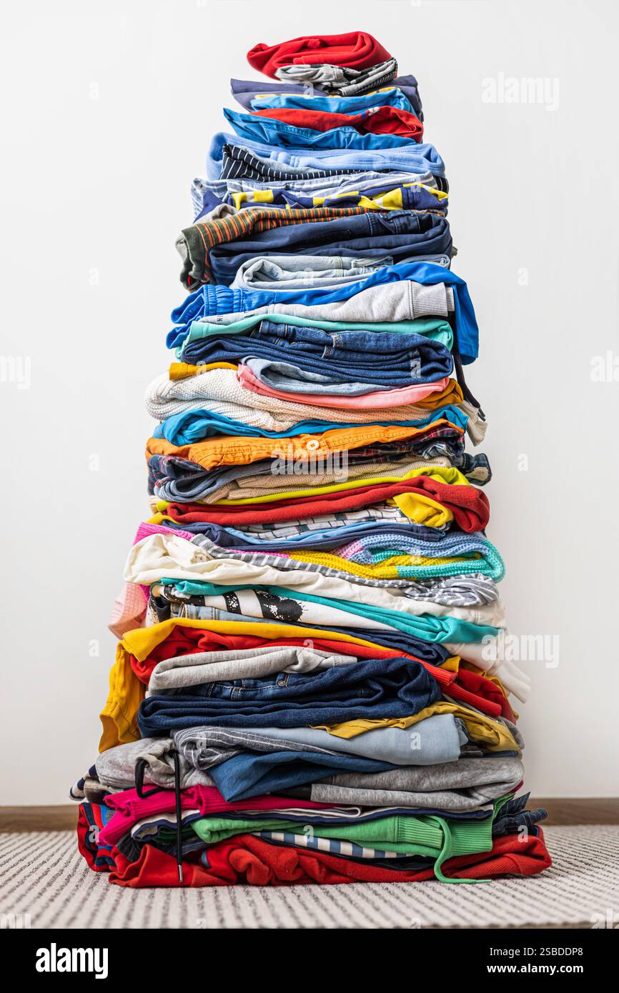 A very tall stack of folded colored clothes for charity, washing ...