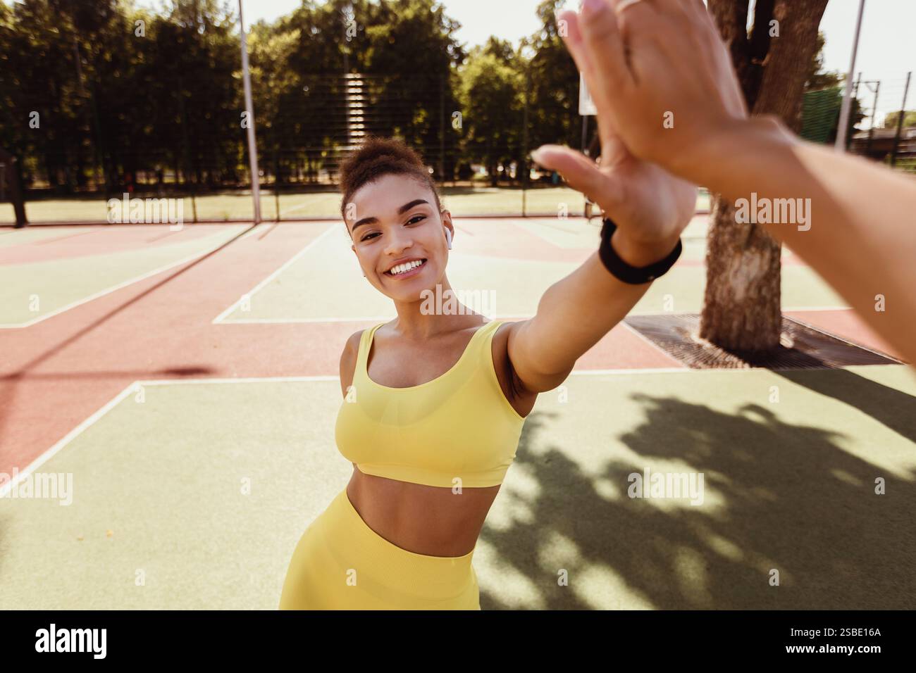 Sporty black woman in yellow sportswear giving high five Stock Photo ...