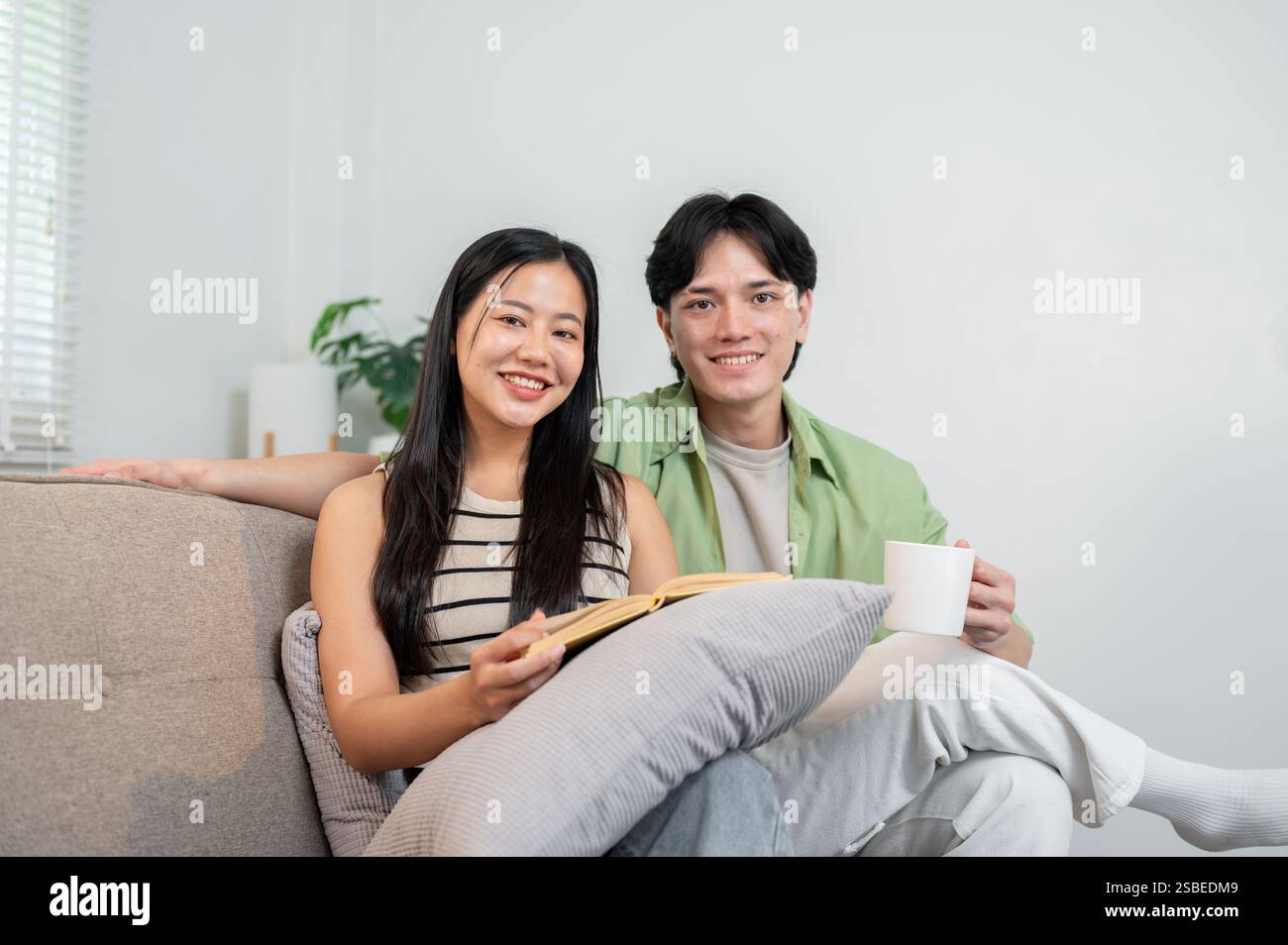A portrait of a lovely, sweet young Asian couple sitting together on a ...