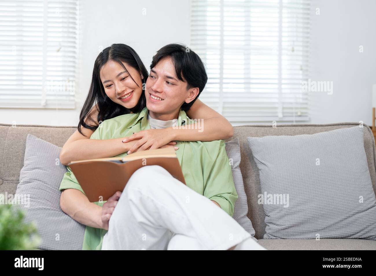 A beautiful, sweet young Asian girl is hugging her boyfriend from ...