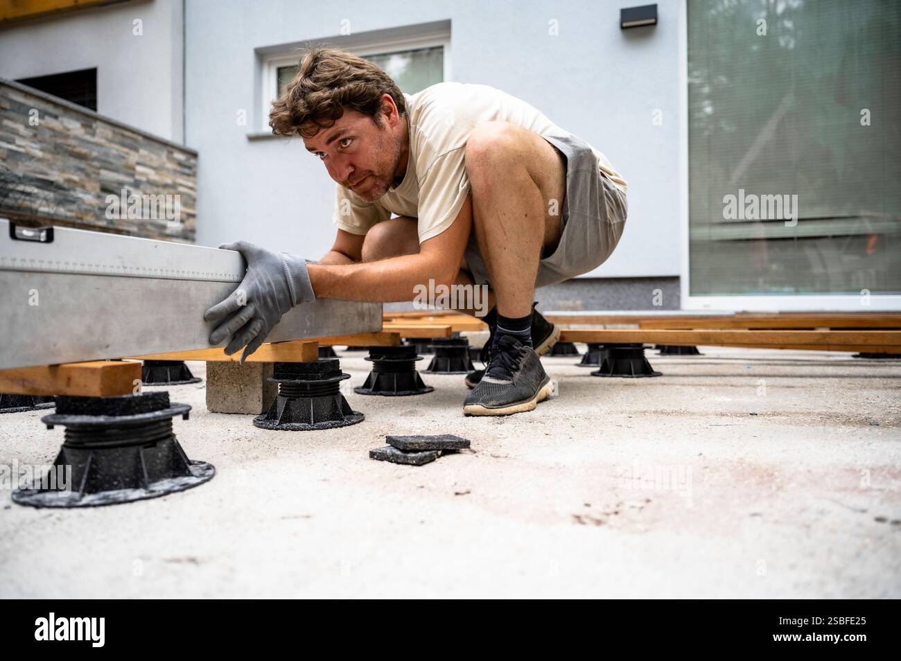 A dedicated worker carefully levels wooden beams on adjustable ...