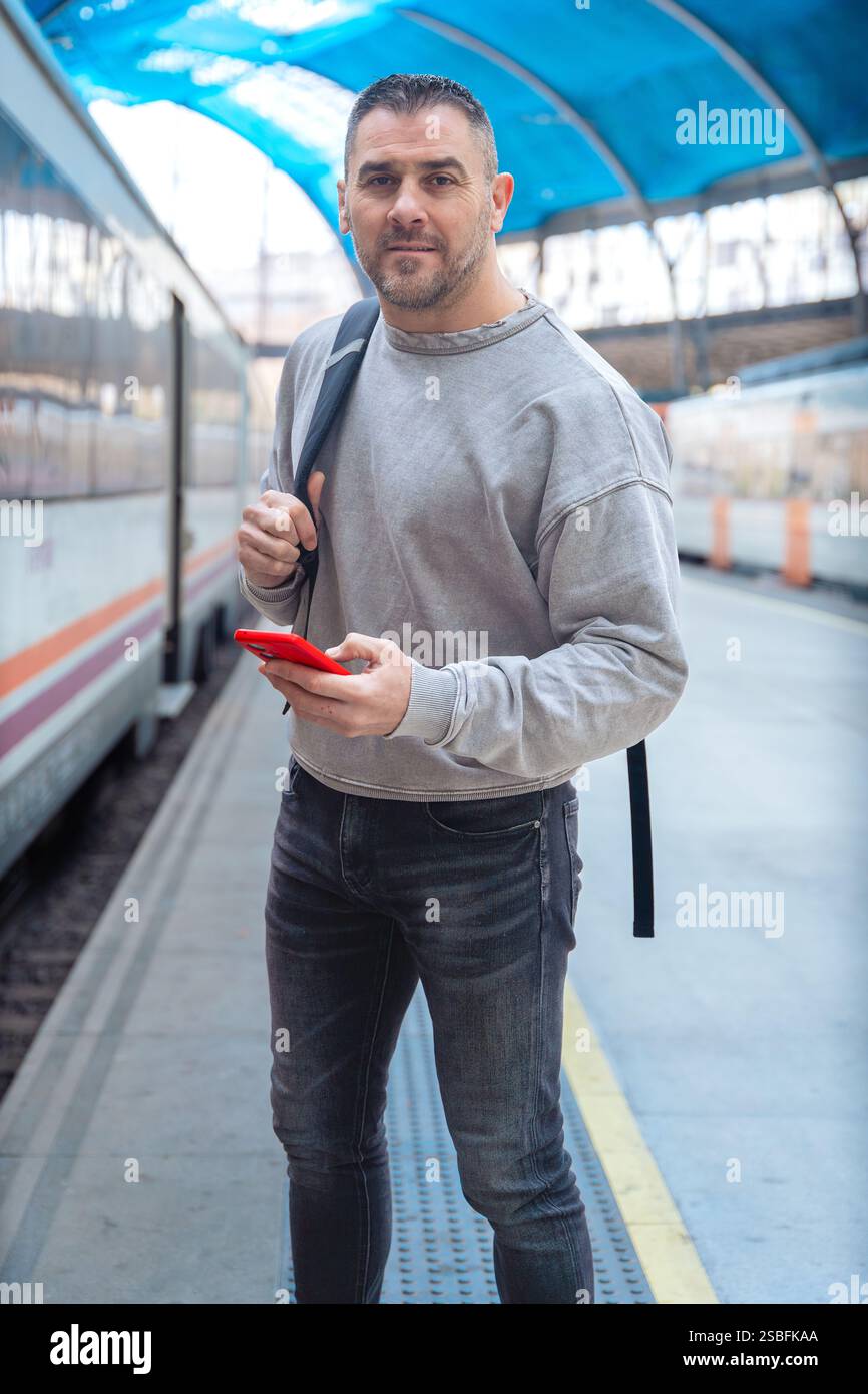 Man Using Red Smartphone at Train Station.Vertical Stock Photo