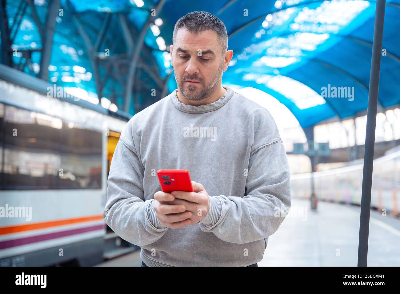 Man using smartphone at train station while traveling Stock Photo