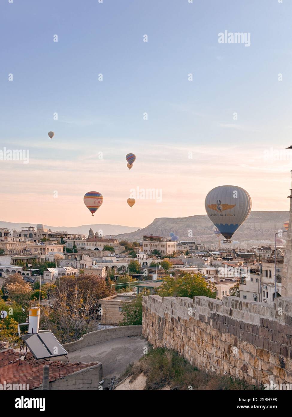 Hot air balloons floating over small town in Cappadocia, Turkey at sunrise - Smartphone Captured Stock Image