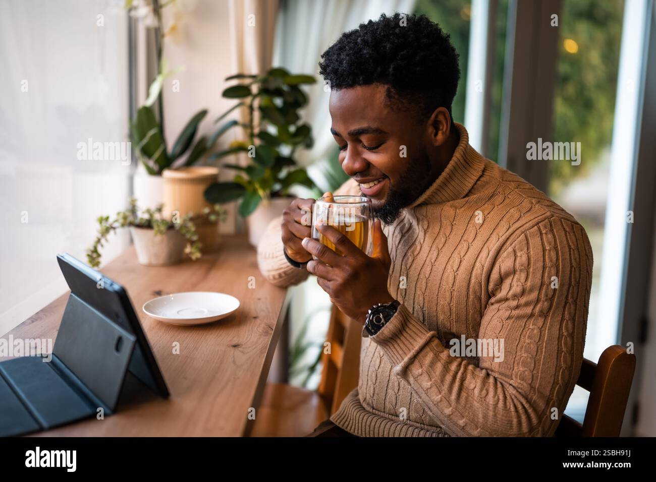 Young man using digital tablet to communicate online. He is sitting in bar,drinking tea and having video call. Stock Photo