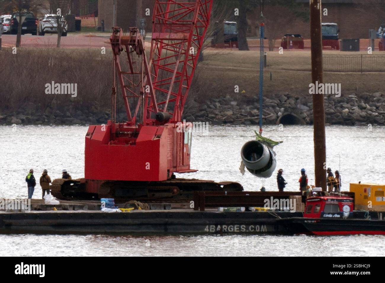 Rescue and salvage crews pull up a plane engine as cranes work near the ...
