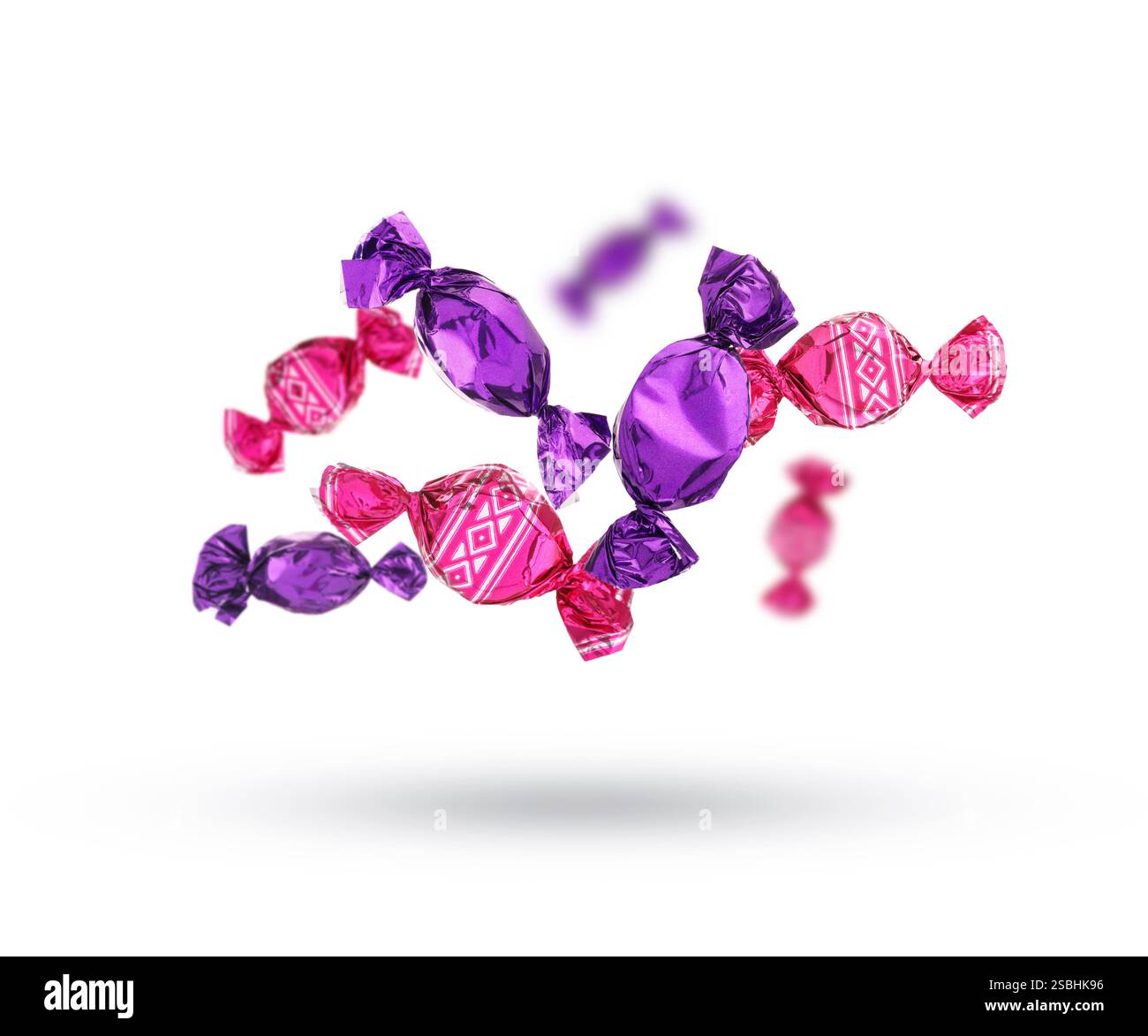 Candies in bright wrappers falling on white background Stock Photo