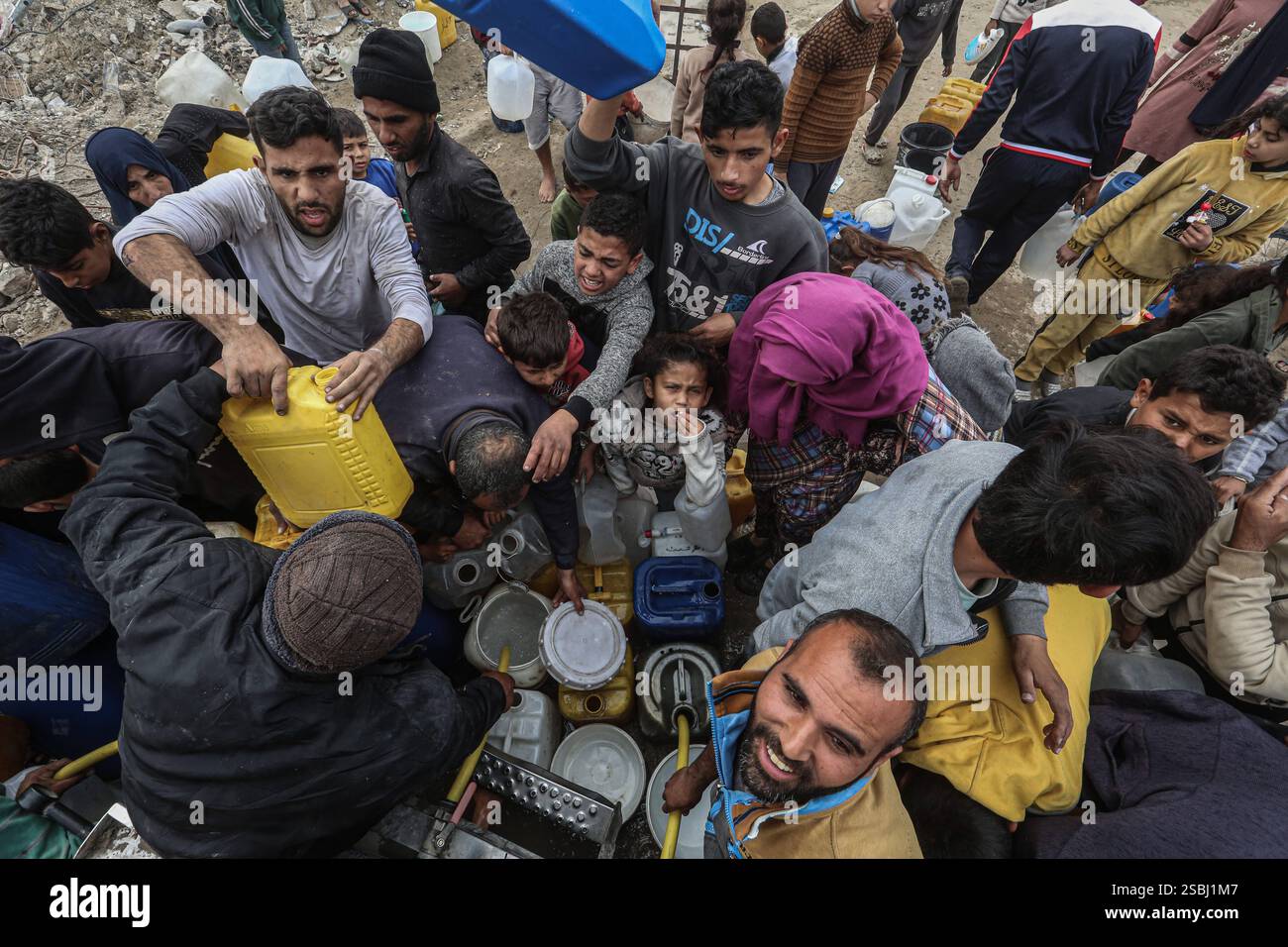 Palestinians try to collect water from a drinking water truck in ...