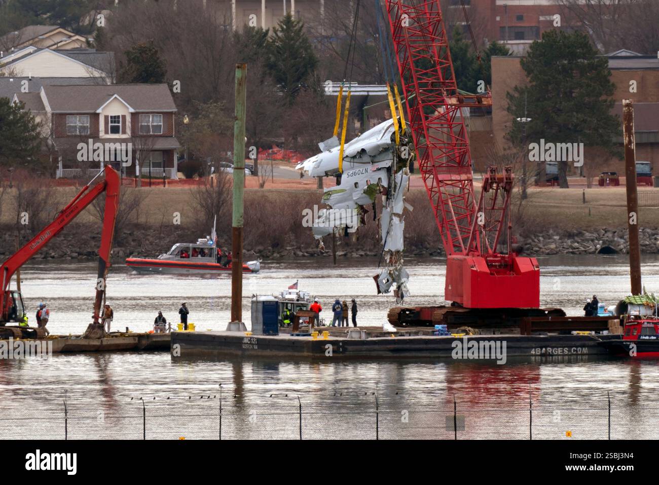 Rescue and salvage crews with cranes pull up the wreckage of an ...