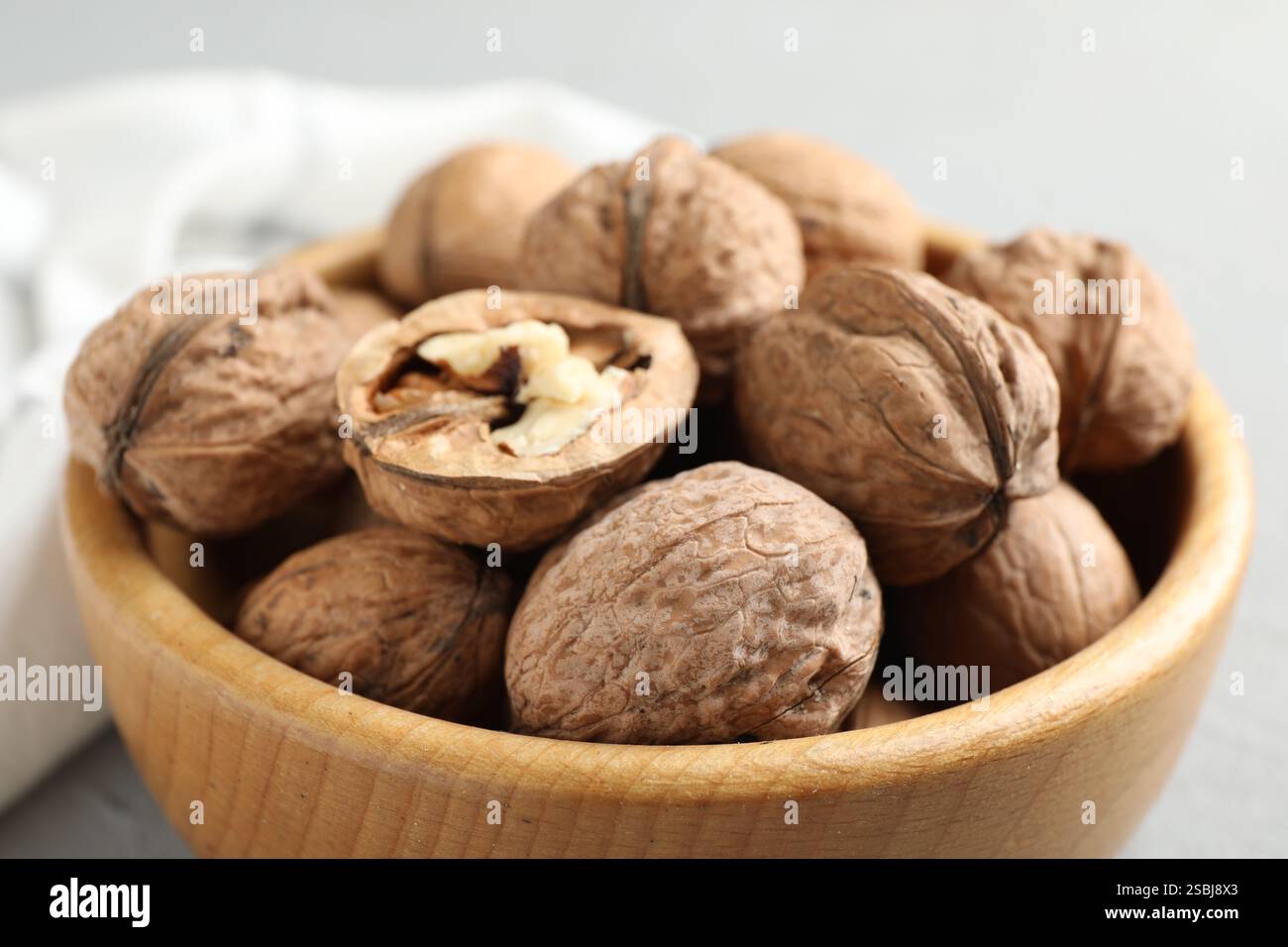 Fresh walnuts in bowl on gray table, closeup Stock Photo