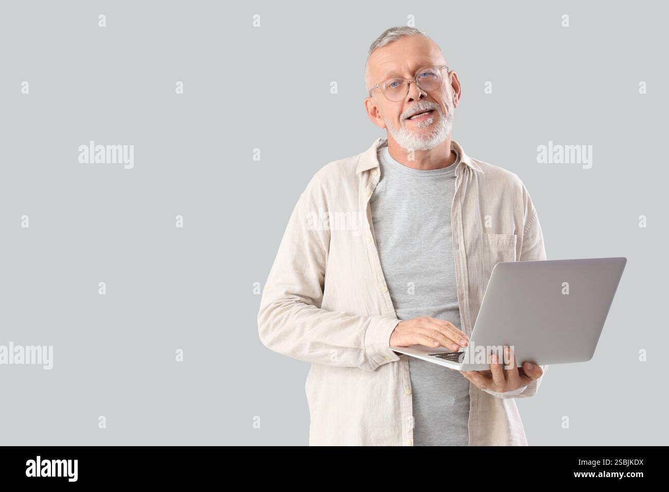 Mature programmer working with laptop on light background Stock Photo