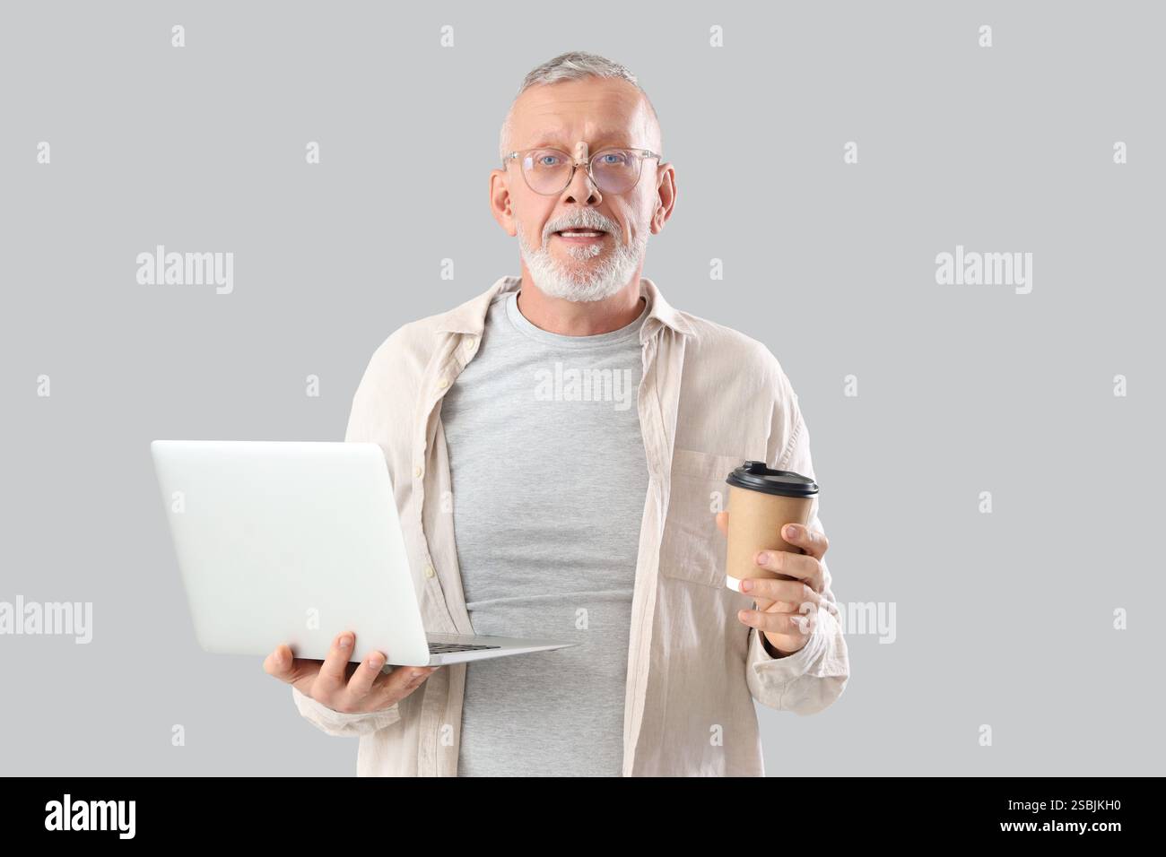 Mature programmer with laptop and coffee cup on light background Stock Photo