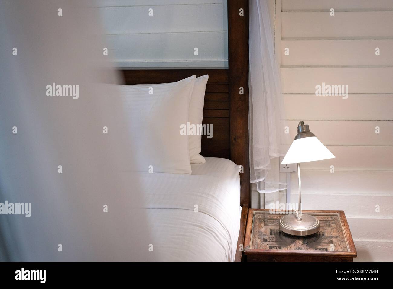 Bedside with side table and lamp on top of it. Cosy living. Stock Photo