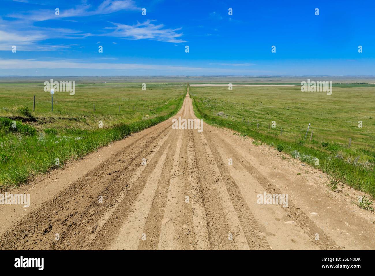 Dirt road with a blue sky in the background. There is a sign on the ...