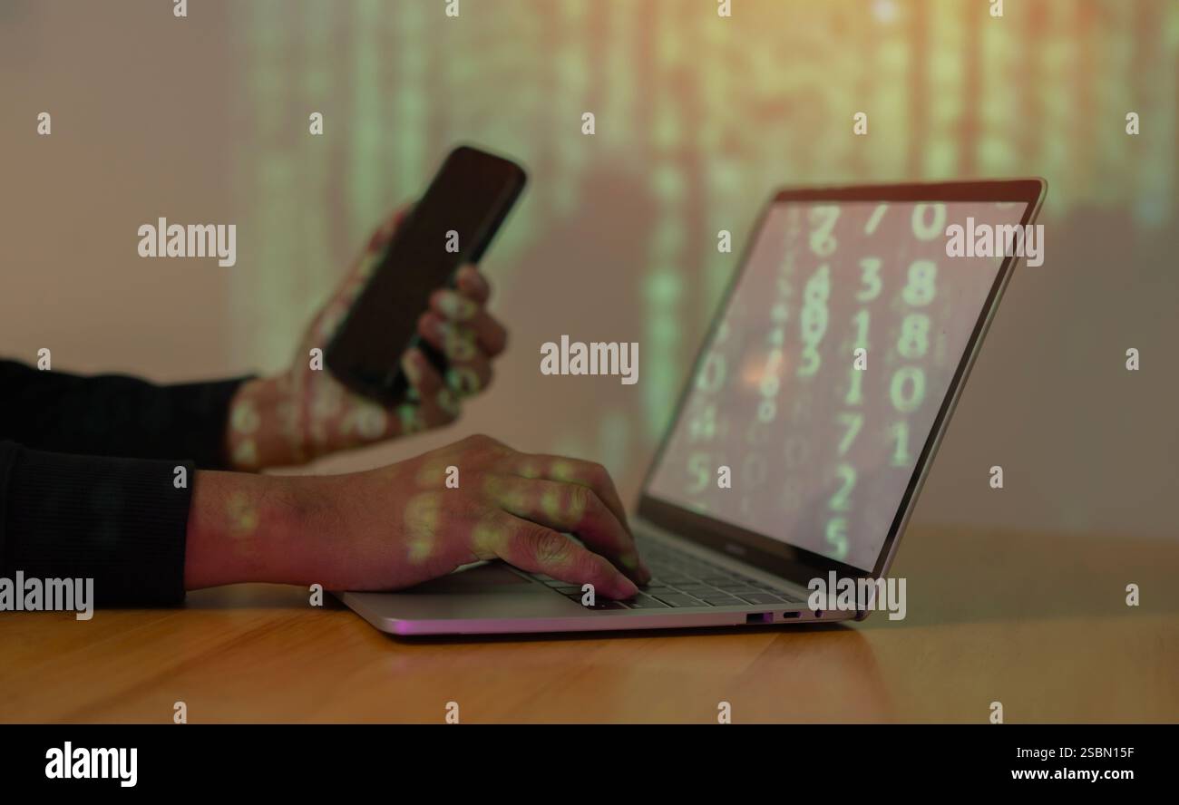 Hooded computer hacker use phone and stealing information with laptop. Selective focus. Stock Photo