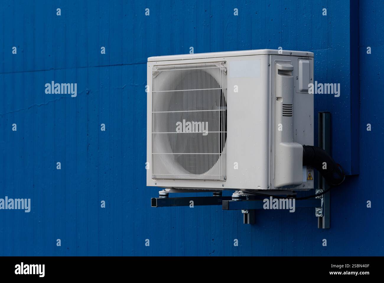 A white air conditioning unit is installed on a blue wall, showcasing ...