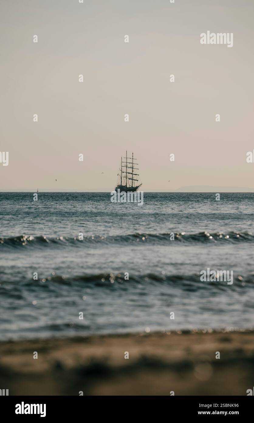 A large ship sails in the ocean, with the sky in the background. The scene is calm and peaceful, with the ship being the only object visible Stock Photo