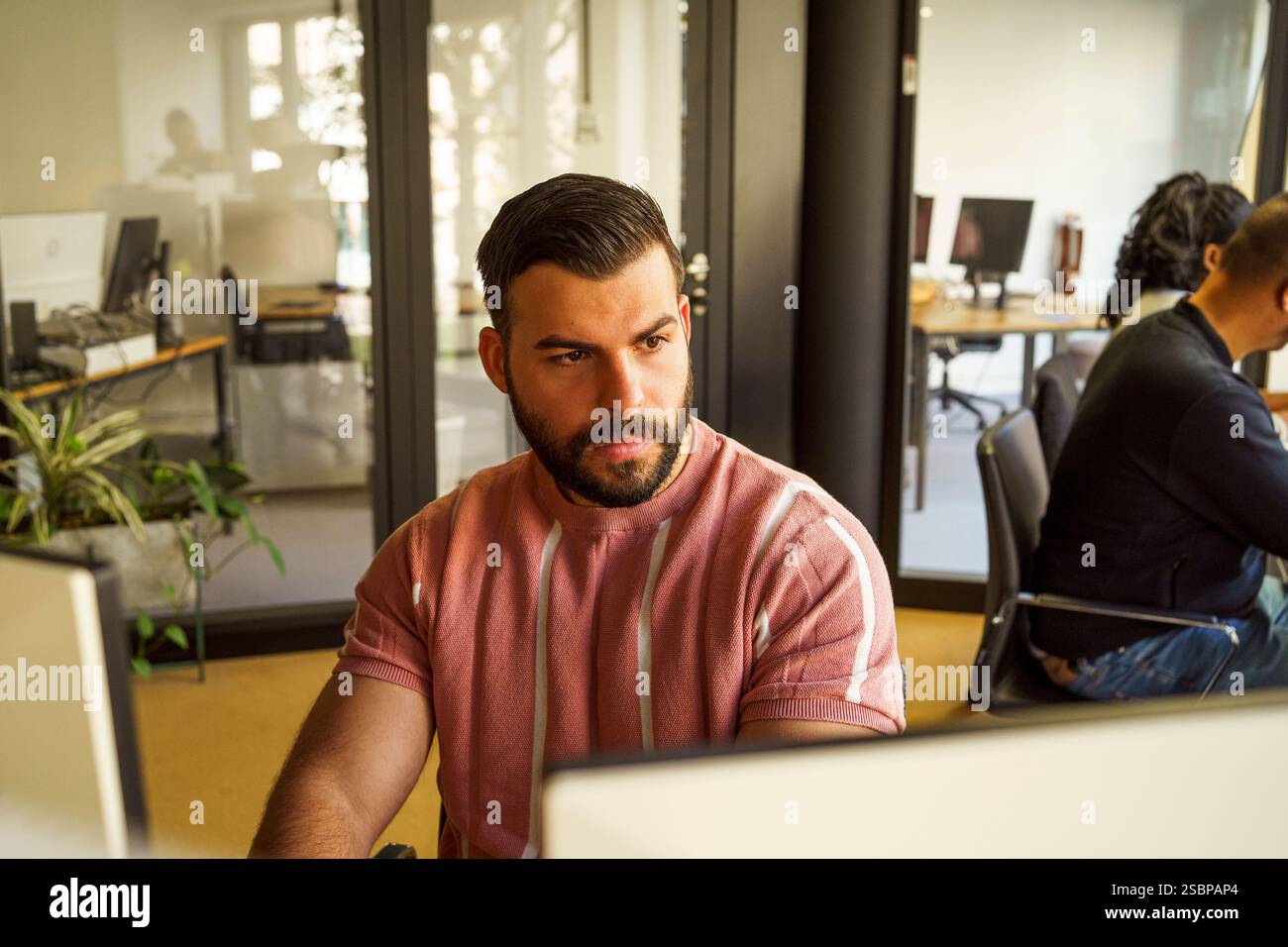 Focused male computer programmer working in tech startup office Stock Photo