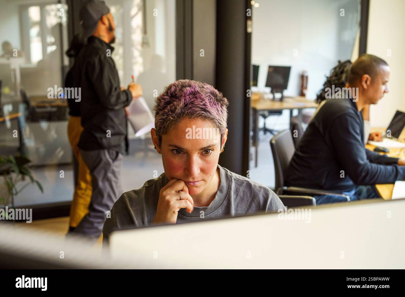 Focused non-binary computer programmer working in office Stock Photo